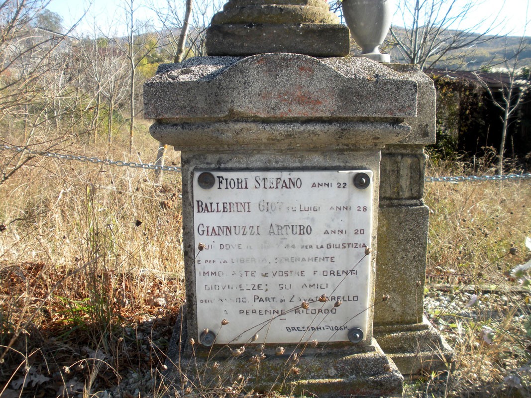 Cippo commemorativo dedicato a Fiori Stefano, Ballerini Giudico e Gianuzzi Arturo, immerso nella natura.