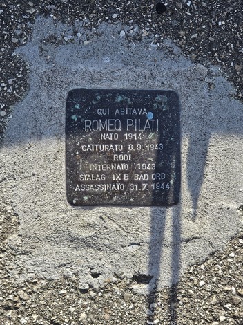 Pietra d'inciampo in metallo scuro incassata nel pavimento, con iscrizione commemorativa.