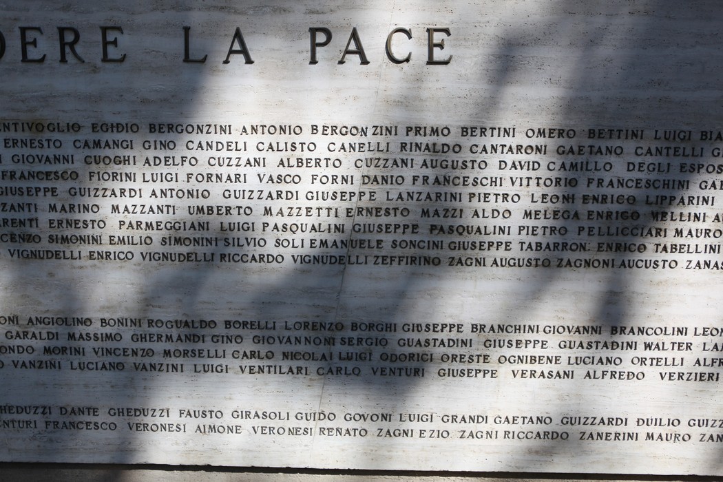 Monumento ai Caduti, con iscrizioni commemorative su una parete di marmo, in un ambiente sereno e riflessivo.