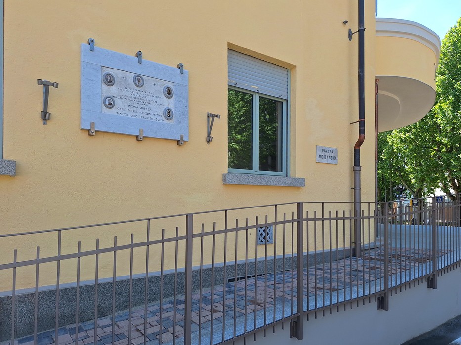 Lapide commemorativa dedicata ai fucilati di Caselle, situata su una parete di edificio giallo.
