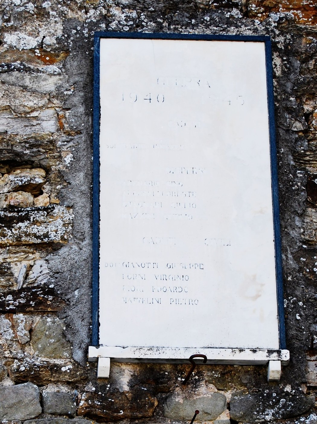 Lapide commemorativa che onora i caduti di guerra, situata su una parete di pietra.