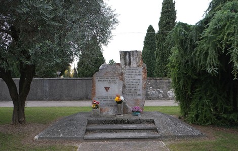 Monumento commemorativo ai caduti nei campi di sterminio nazisti, situato in un'area verde.