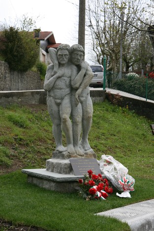 Scultura commemorativa dei partigiani, con due figure che simboleggiano resistenza e sacrificio. Fiori ai piedi.