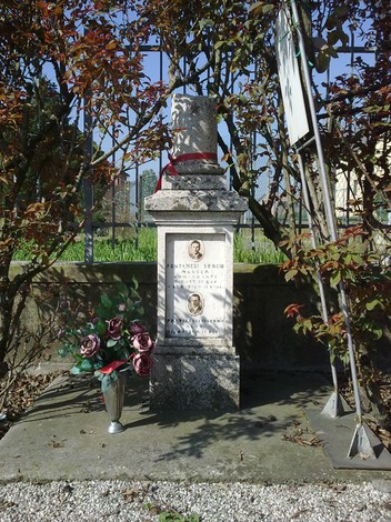 Cippo commemorativo in ricordo di Fontanesi e Pratissoli, adornato con fiori e circondato da natura.