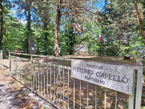 Lapide dedicata alla Resistenza, circondata da alberi e recintata, con elementi commemorativi visibili.