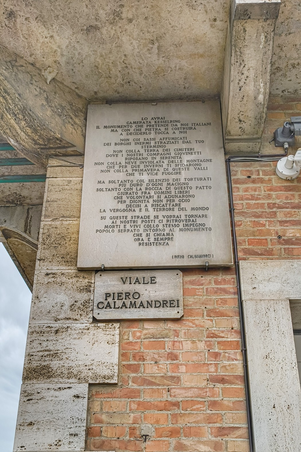 Lapide commemorativa in pietra, con iscrizioni storiche su tortura e ingiustizia, affissa su un muro in città.