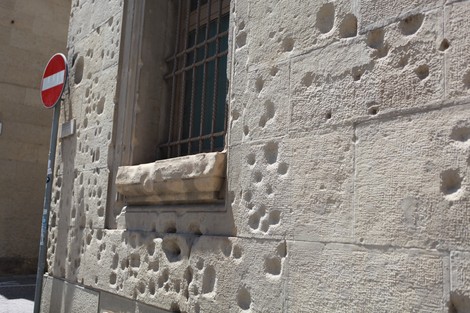 Lapide commemorativa dei danni causati dal bombardamento del 24 luglio 1943, con segni visibili sulla facciata.