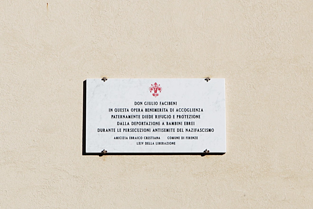 Lapide commemorativa di Don Facibeni, riconosciuto per la sua opera di accoglienza e protezione durante la guerra.