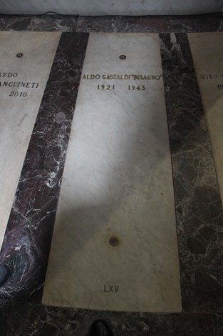 Lapide in marmo dedicata a Aldo Gastaldi, con incisi nome e anni di nascita e morte, su fondo di marmo scuro.