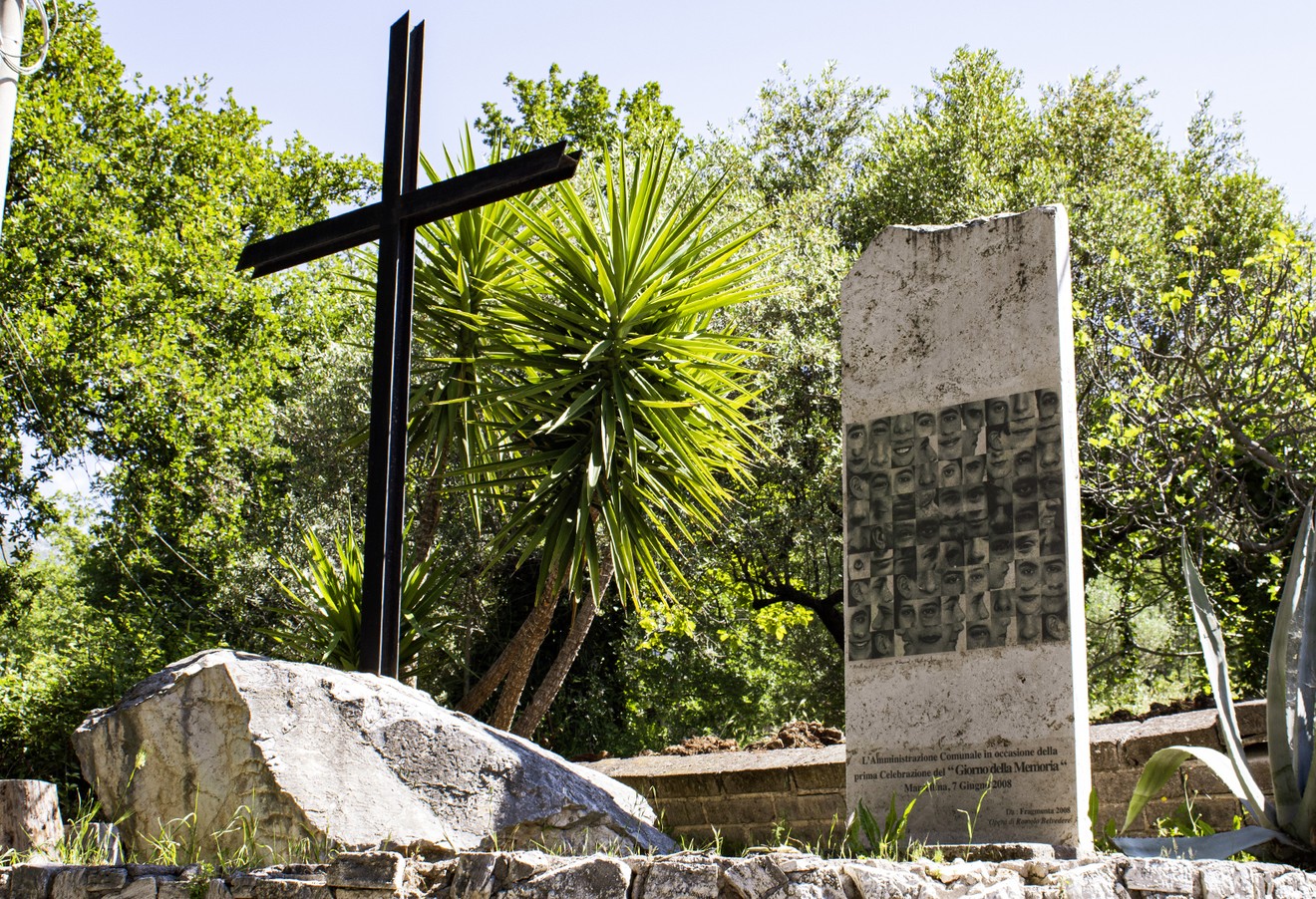 Monumento commemorativo che onora i fucilati di Fonte Paolone, immerso nella natura.