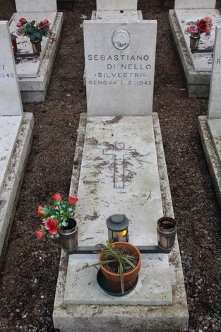 Tombe bianche adornate con fiori e luci, commemorano i caduti per la Libertà. Atmosfera di rispetto e memoria.
