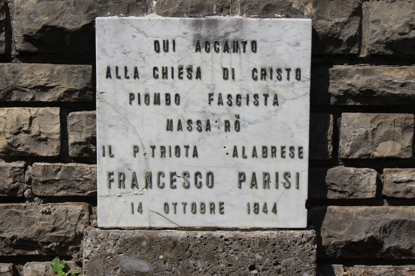 Lapide commemorativa in marmo dedicata a Francesco Parisi, situata vicino a una chiesa.