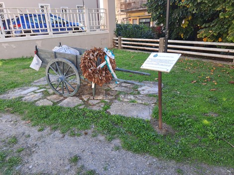 Carretto delle lavandaie in un contesto verde, con fogliame secco decorativo e segnaletica informativa.