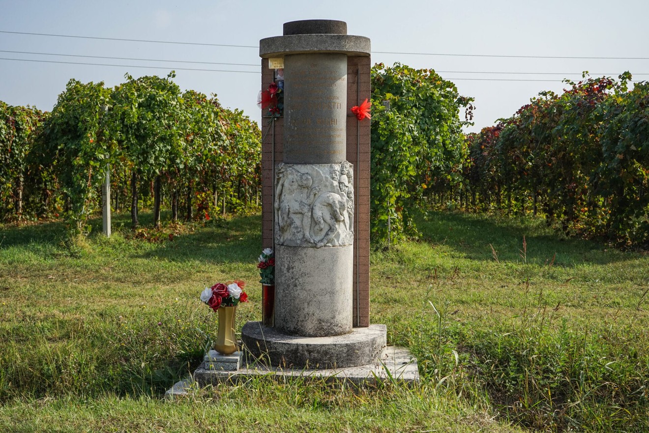 Monumento a Guidetti e Righi, circondato da vigne, con decorazioni floreali e una scultura commemorativa.