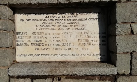 Lapide commemorativa dedicata ai partigiani uccisi, con nomi e date incisi su pietra.