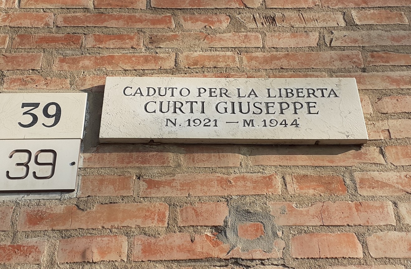 Lapide commemorativa di Curti Giuseppe, caduto per la libertà nel 1944, situata su un muro di mattoni.
