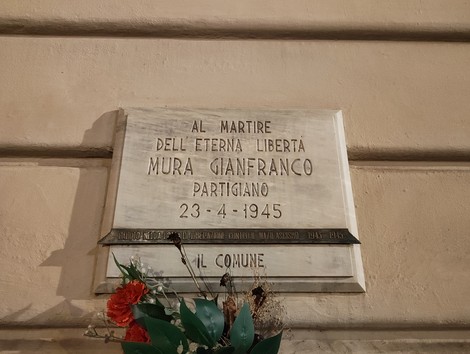 Lapide commemorativa dedicata a Gianfranco Mura, partigiano, affissa a una parete.