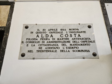 Lapide commemorativa in memoria di Alda Costa, insegnante e martire antifascista, situata in un ospedale.