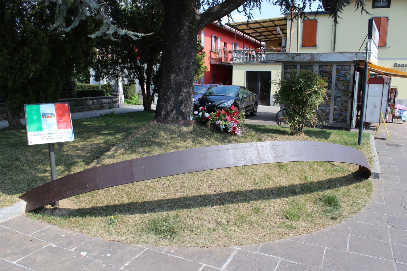 Monumento ai caduti partigiani, caratterizzato da una struttura in metallo, immerso in un verde parco urbano.