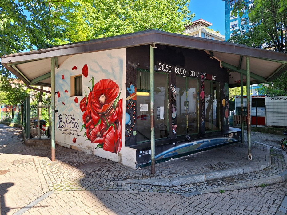 Murale colorato su edificio, con fiori rossi e graffiti che rappresentano arte urbana vivace.