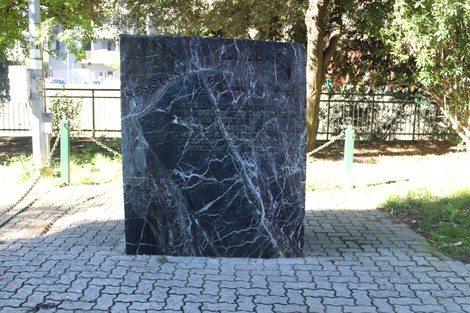 Monumento alla Resistenza con superficie in marmo scuro, circondato da un'area verde e sentieri.