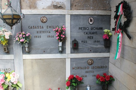 Sacrario dei partigiani con tombe decorate da fiori e commemorazioni. Atmosfera di rispetto e memoria.