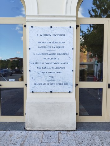 Lapide in marmo dedicata a Webben Facchini, partigiano caduto per la libertà, presso un edificio pubblico.