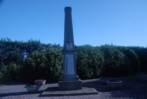 Monumento ai Partigiani caduti all'Olmo, obelisco con base circondata da aiuole verdi e fiorite.
