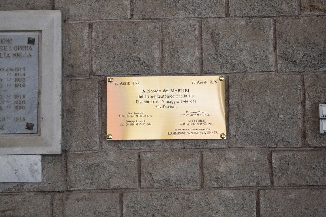 Lapide commemorativa con targa dedicata ai martiri, collocata su una parete di pietra.