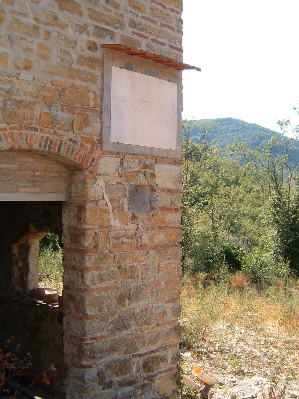 Lapide di Morlione, monumento in pietra, immerso nella natura e parte di una costruzione storica.