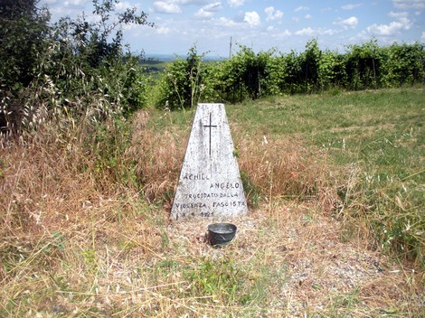 Cippo commemorativo dedicato ad Achilli, immerso nella natura e circondato da vigne.