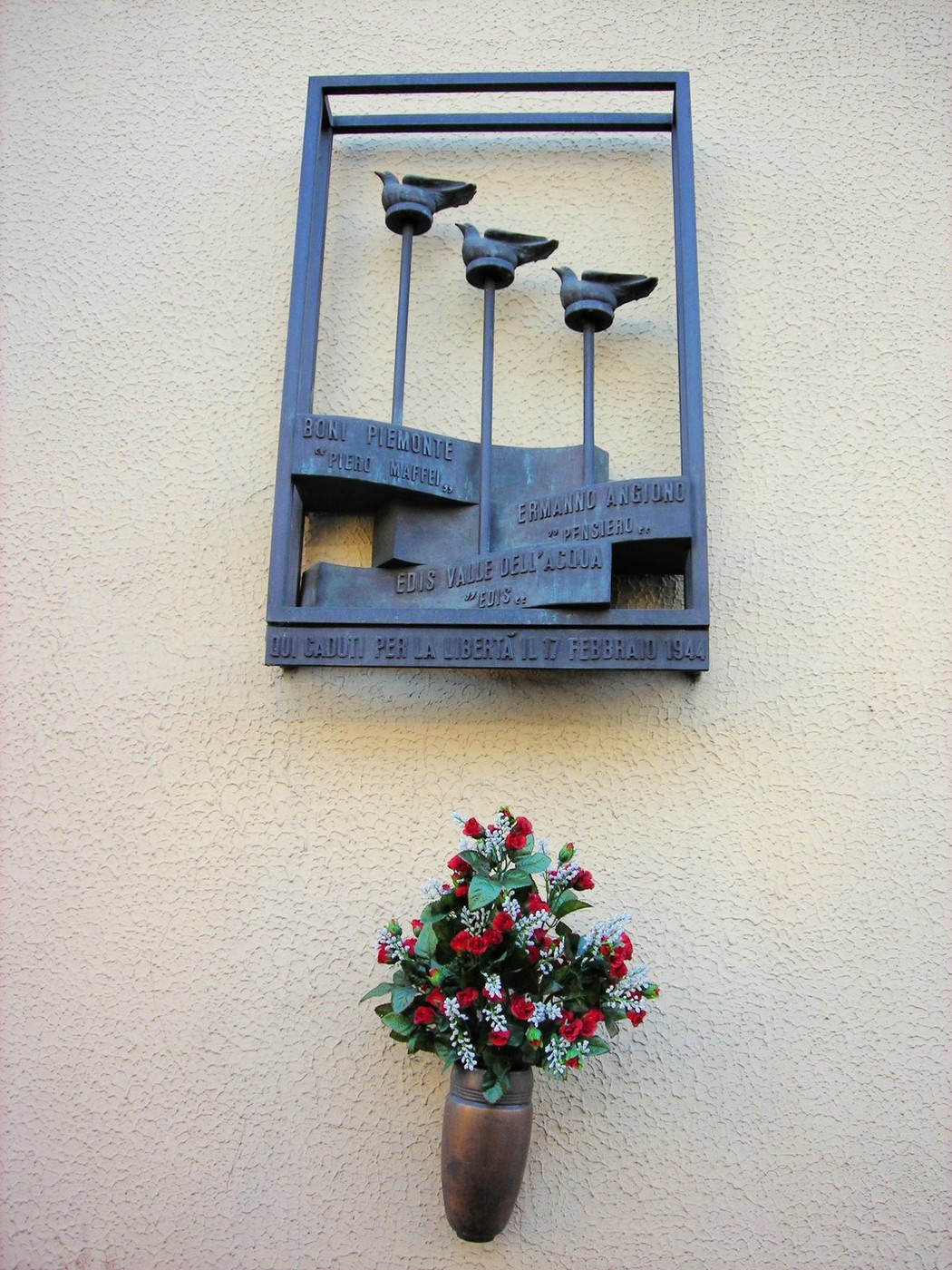 Monumento commemorativo in onore di Piemonte, Angiono e Valle dell'Acqua, con fiori freschi.