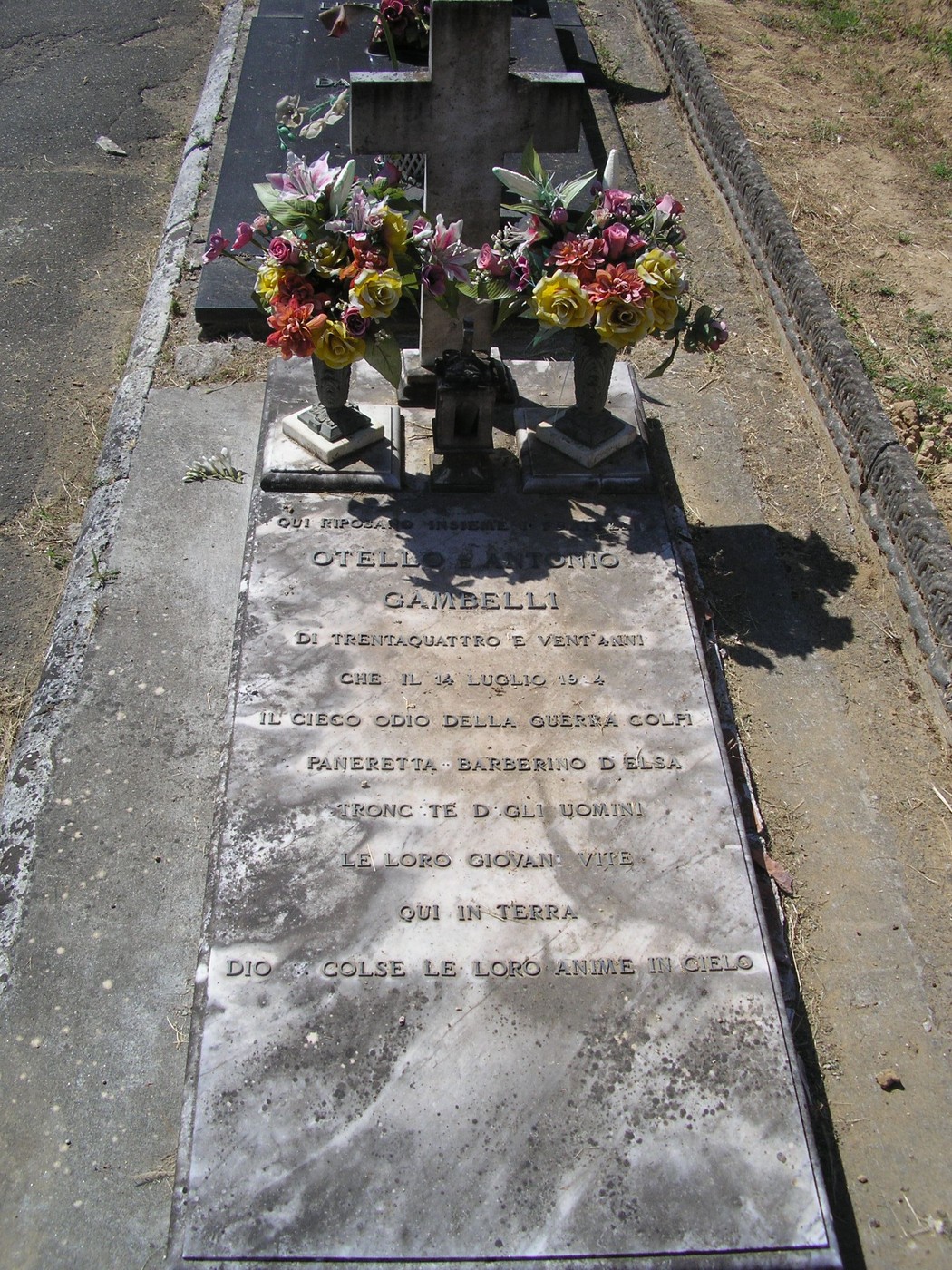 Sepolcro dei Gambelli con lapide decorata e fiori, situato in un luogo di memoria e rispetto.