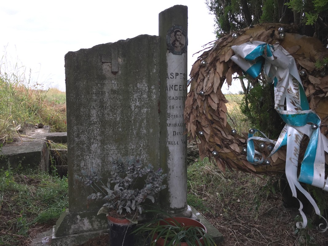 Monumento ad Aspesi, commemorazione con corona e decorazioni, immerso nella natura e nel silenzio.