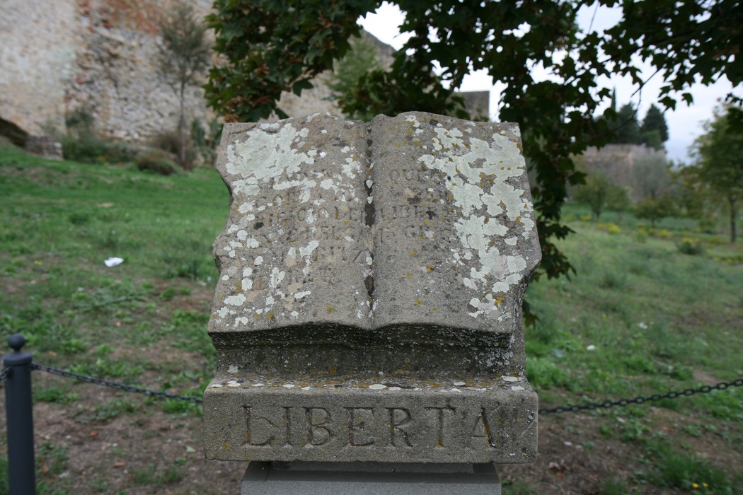 Cippo a Meuret con iscrizioni commemorative, simbolo di libertà e storia locale.