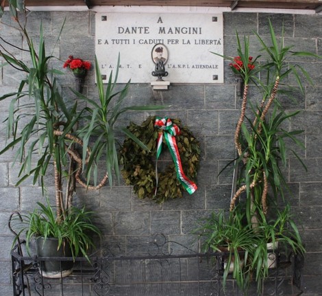 Monumento a Mangini, con piante decorative e una corona di alloro, in memoria dei caduti per la libertà.