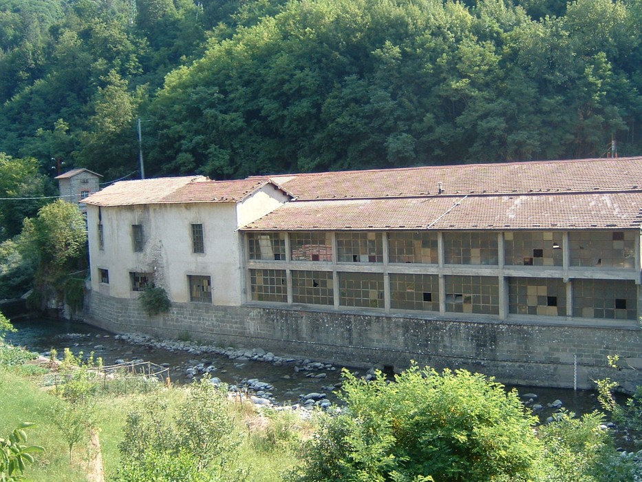 Lapide del Lanificio Tronci: edificio storico industriale situato lungo un corso d'acqua, circondato da verde.