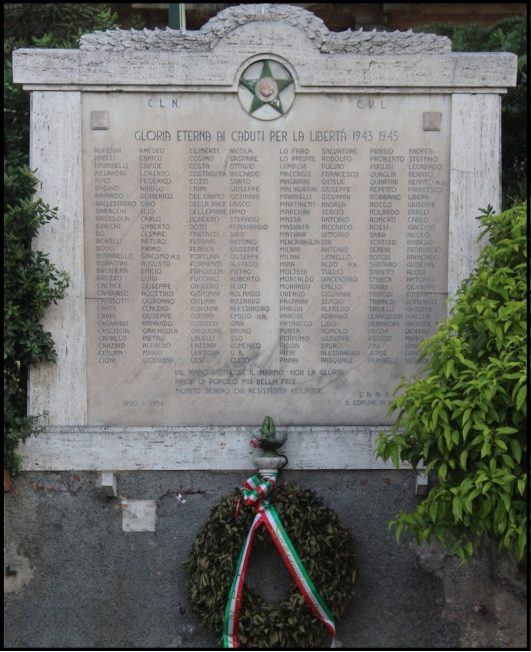 Lapide commemorativa ai caduti per la Libertà di Sampierdarena, incorniciata da una corona di alloro.