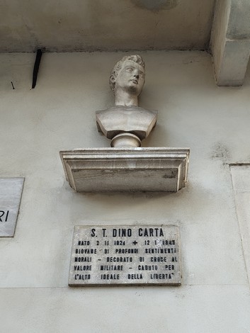 Busto di Dino Carta su una lapide commemorativa affissa a un muro, commemorando il suo valore e la sua libertà.