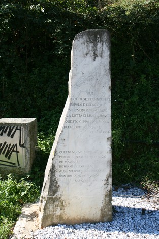 Il Vecchio Cippo della Foce, monumento storico, si erge tra la vegetazione, testimone di eventi passati.
