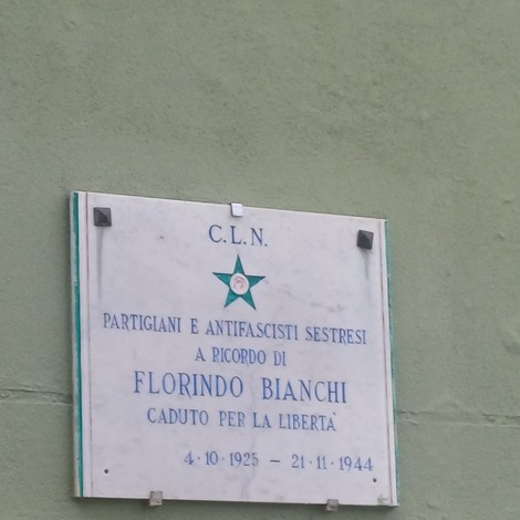 Lapide marmorea con stella verde del C.L.N. e iscrizione, fissata su parete esterna.
