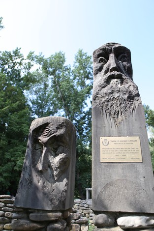 Monumento ai caduti della valle del Panaro, due sculture di pietra con volti espressivi in un contesto naturale.