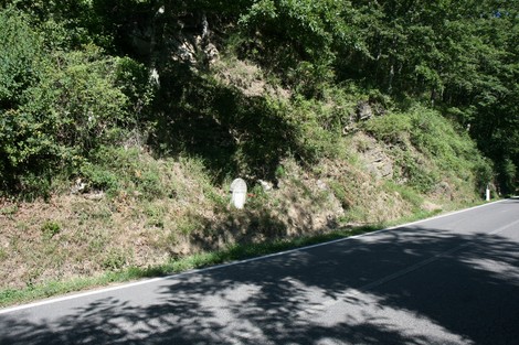 Cippo commemorativo dedicato a Maria Fini, immerso nel verde lungo una strada di campagna.
