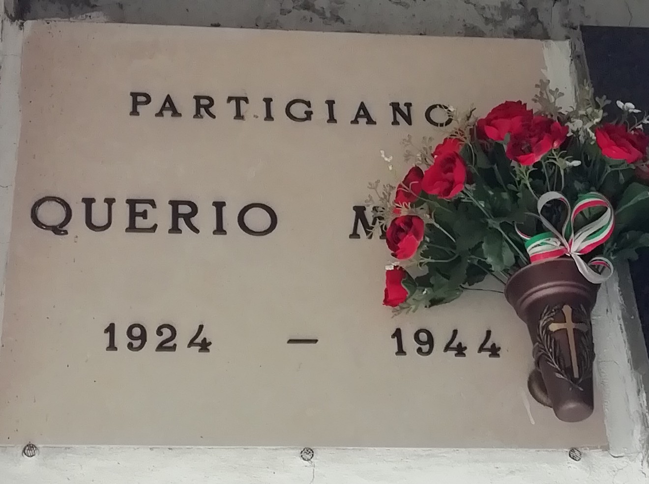 Sepolcro dedicato a Querio, partigiano, con fiori e decorazioni commemorative. Anni 1924-1944.