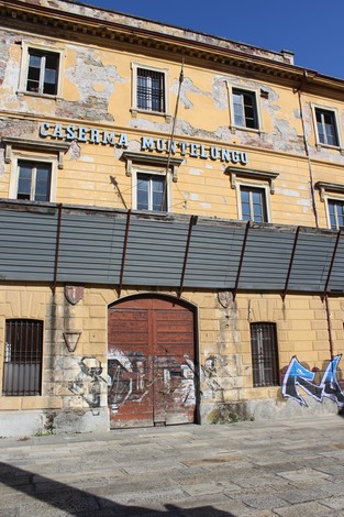 Soglia d'ingresso della Caserma Montelungo, con muri deteriorati e graffiti visibili.