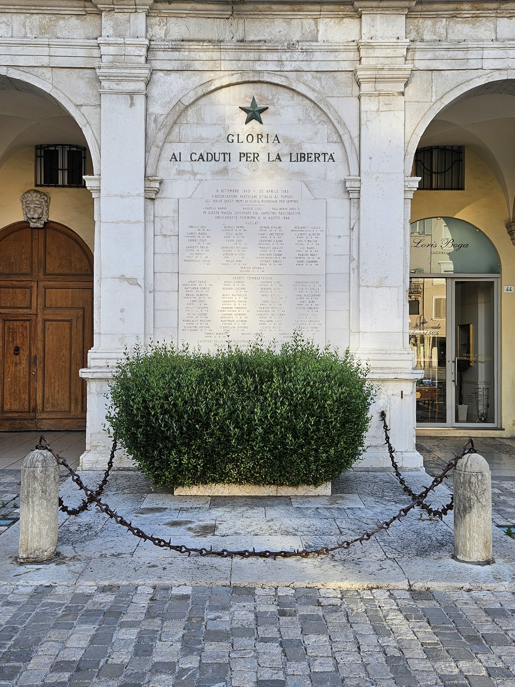 Lapide commemorativa con iscrizioni, dedicata ai Caduti per la Libertà, incastonata in un'architettura storica.
