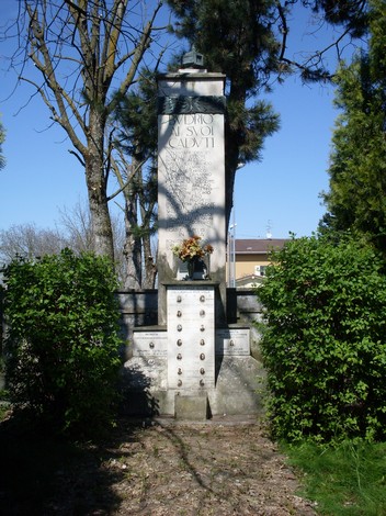 Monumento ai Caduti di Budrio, commemorazione dei soldati, immerso nel verde con fiori e alberi circostanti.