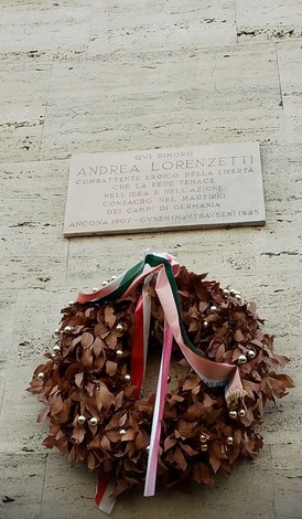 Lapide commemorativa di Andrea Lorenzetti, con una corona di alloro decorata da nastri.