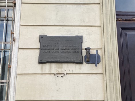 Lapide commemorativa dedicata a Rigat e altri su una facciata storica.