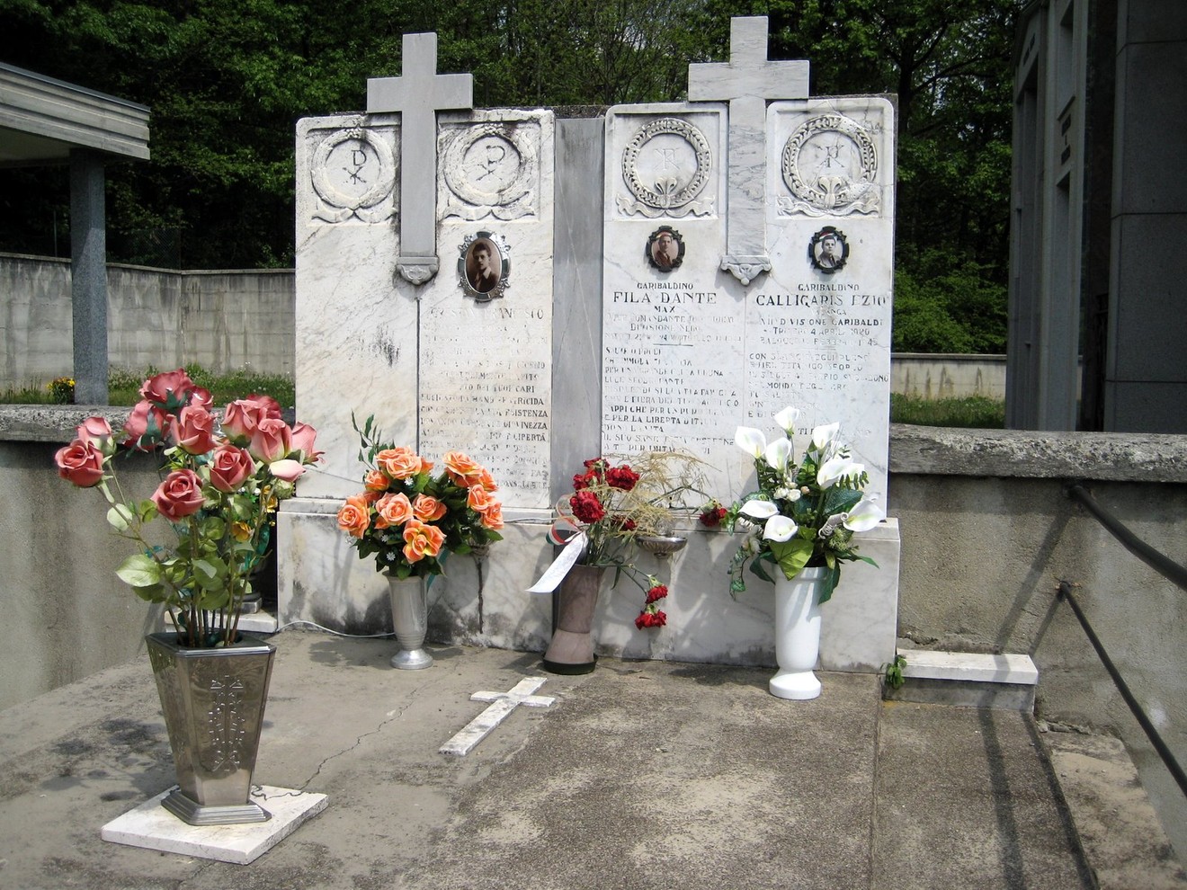 Monumento commemorativo ai partigiani, con fiori e croci in ricordo dei caduti.
